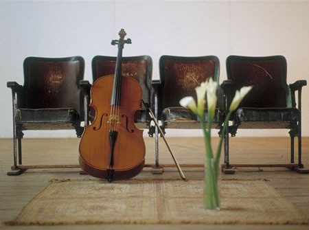 Cello leaning on attached chairs Online now